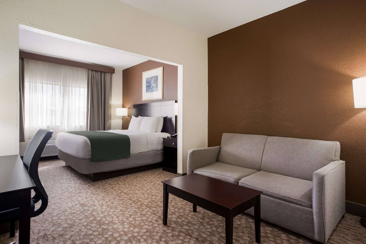 Ein Hotelzimmer mit einem Bett, einer Couch, einem Schreibtisch und einer Lampe.