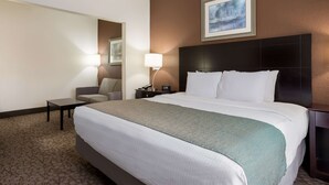 A hotel room with a large bed, a bedside table, a chair, a lamp, and a painting on the wall. - Best Western Kendallville Inn (Kendallville)