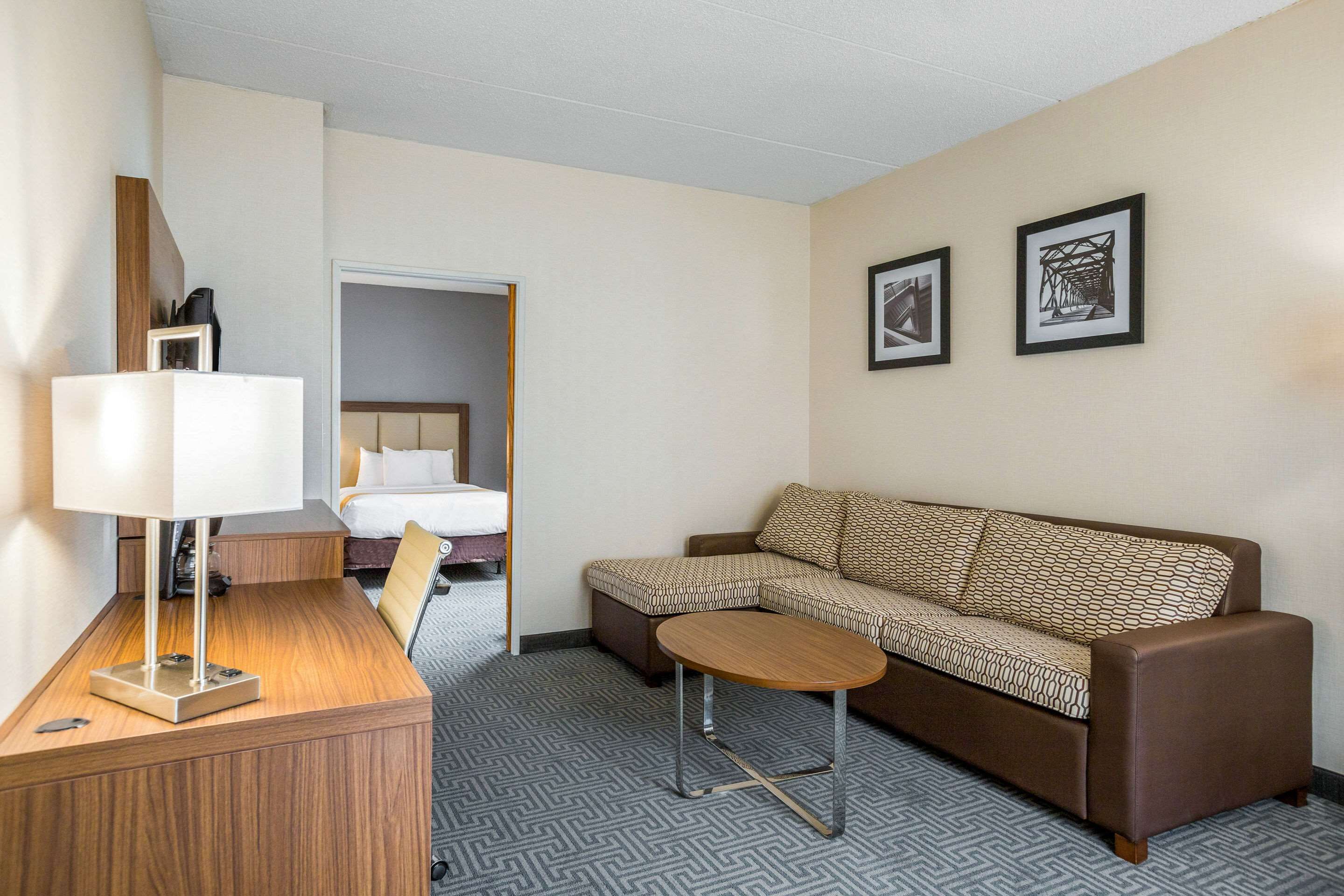 Ein Hotelzimmer mit einer Couch, einem kleinen Tisch, einer Lampe und zwei gerahmten Bildern an der Wand.
