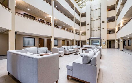 A spacious multi-level lobby with modern furniture and a large screen.
