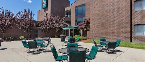 A courtyard with outdoor seating, a brick building, and a sign for Quality Suites.