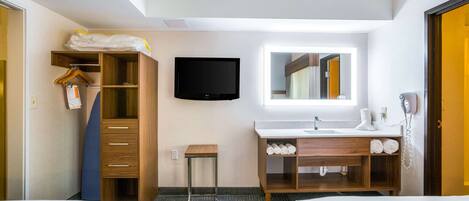 A hotel room with two beds, a wardrobe, a television, a mirror, a sink, and a telephone.
