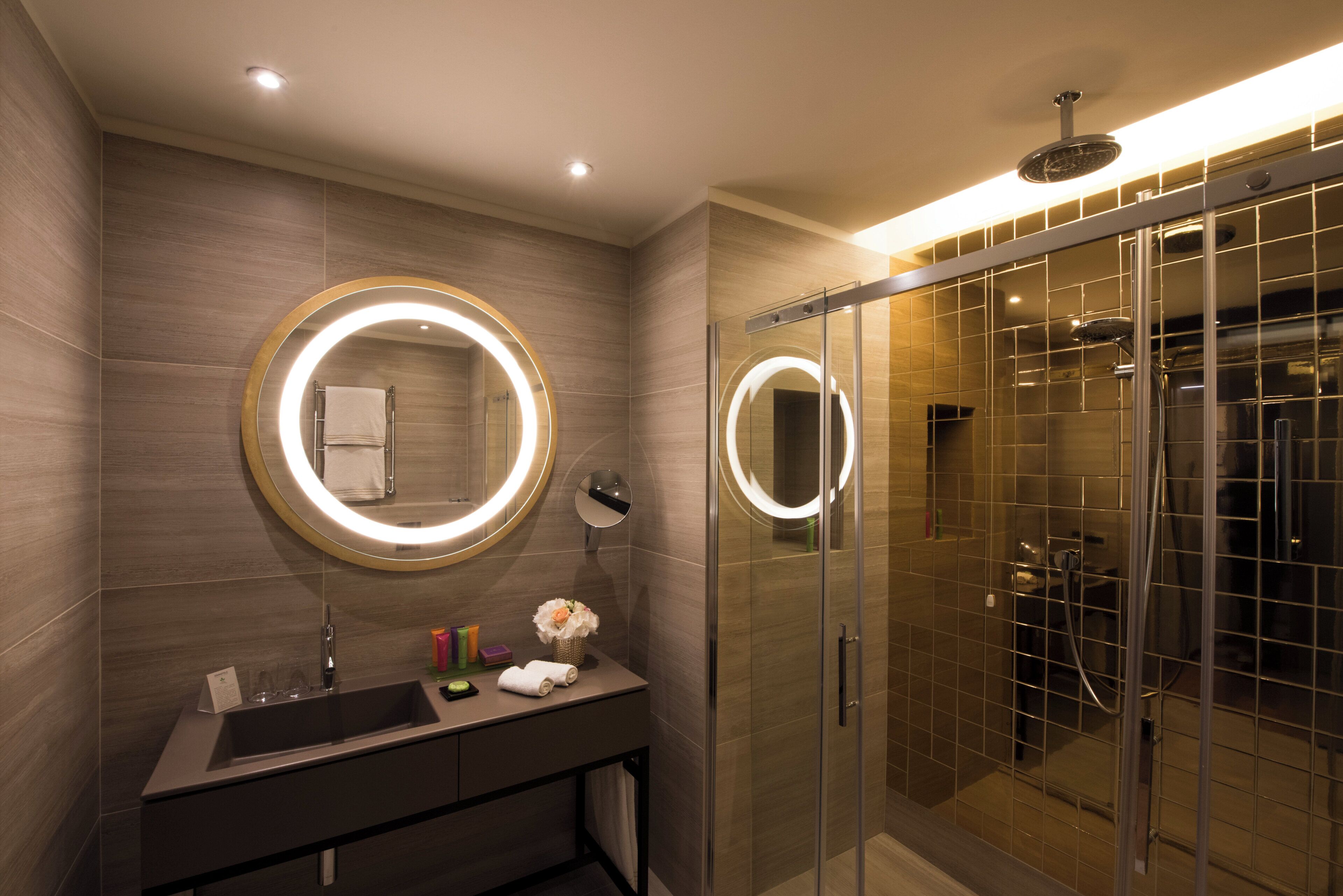 Un baño moderno con lavamanos, espejo y ducha.