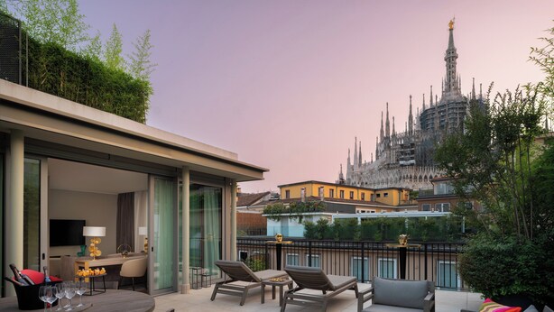 A rooftop terrace with a dining area, lounge chairs, and a view of a historic building. - Rosa Grand Milano - Starhotels Collezione (Milan)