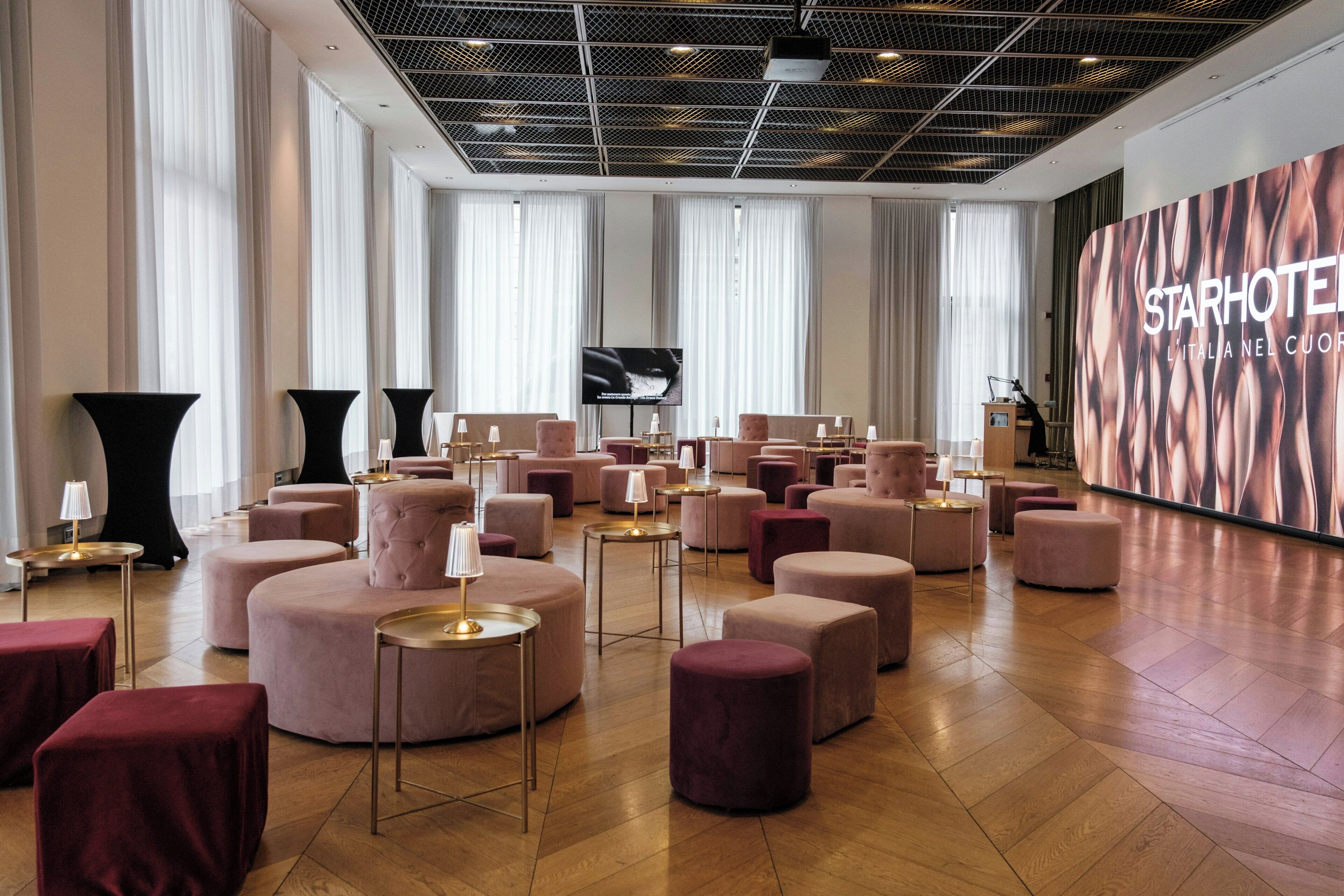 A spacious hotel lobby with multiple seating areas, a large screen, and a prominent StarHotel sign.