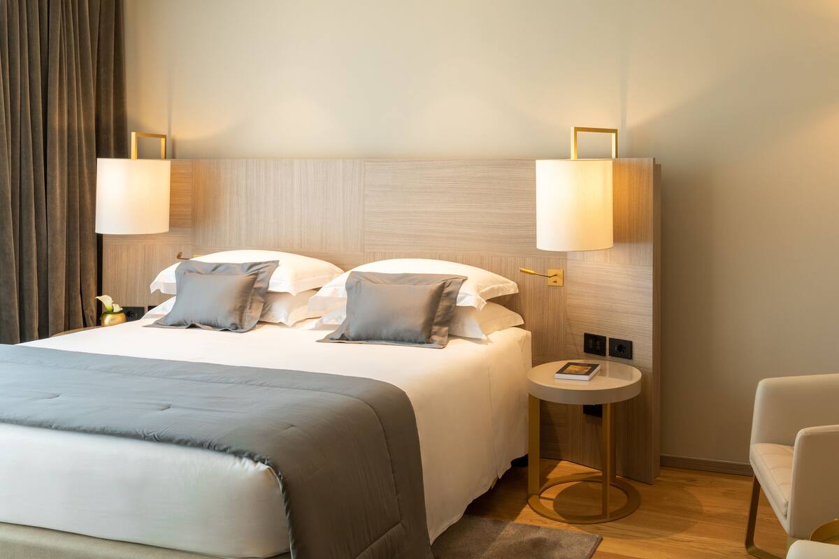 Une chambre d’hôtel avec un grand lit, deux lampes de chevet, une petite table ronde et une chaise.