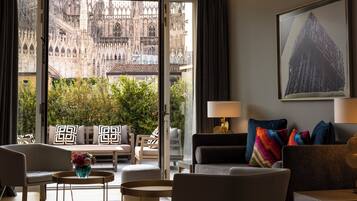 Una camera d'albergo moderna con vista su un'antica cattedrale, un'accogliente area relax e un'opera d'arte contemporanea.