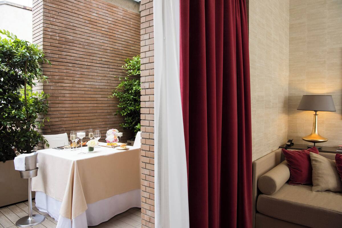 Un coin repas avec une table dressée pour deux personnes, un canapé avec des coussins et une lampe.
