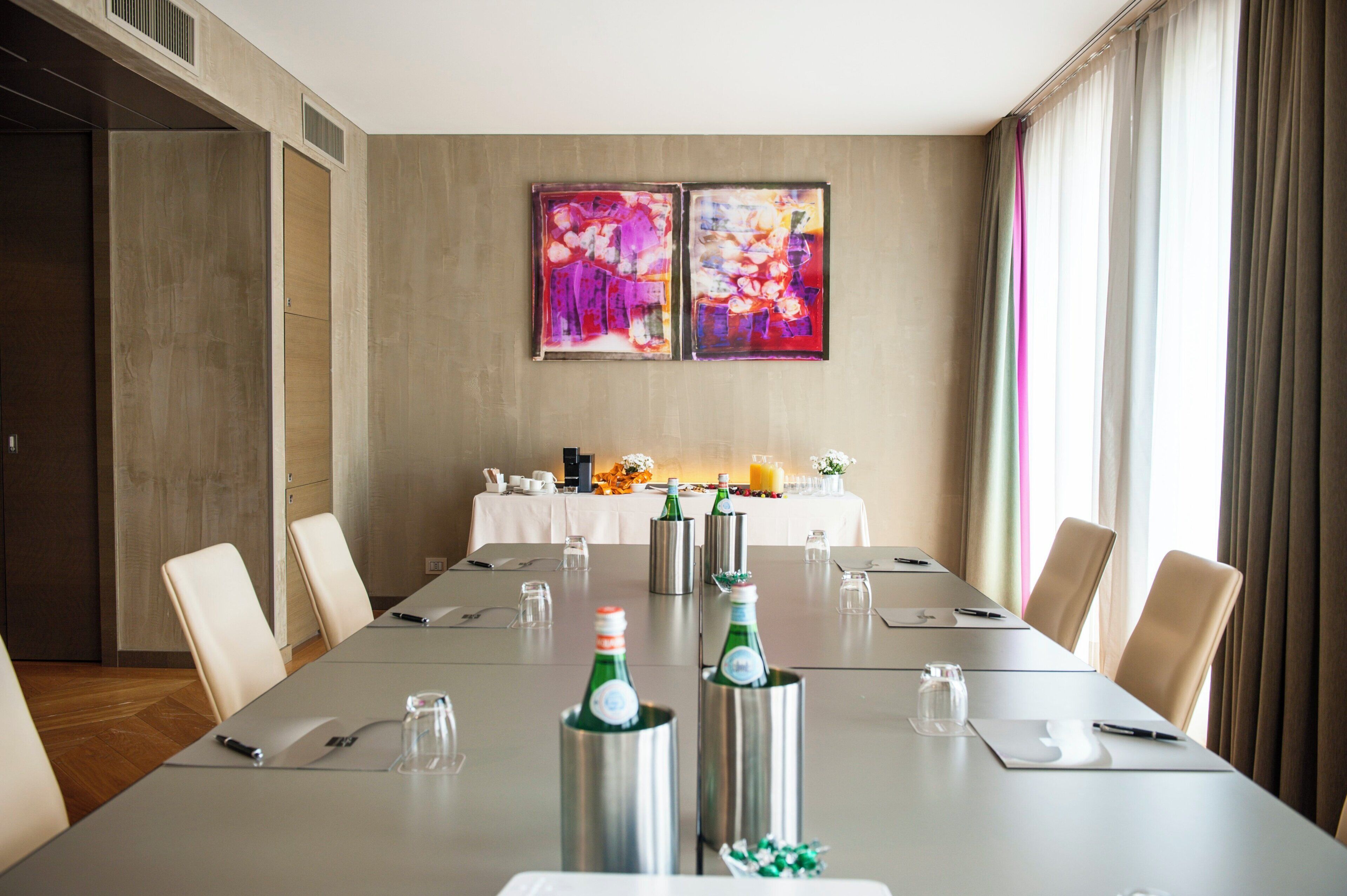 A conference room with a long table, chairs, and two abstract paintings on the wall.