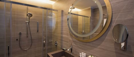 Un bagno moderno con doccia vetrata, uno specchio grande e un mobile lavabo con asciugamani e prodotti da bagno.