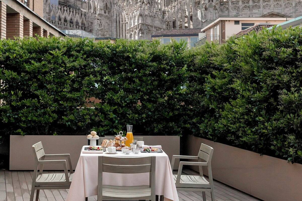 Un coin repas avec une table dressée pour deux personnes, donnant sur une cathédrale de style gothique.