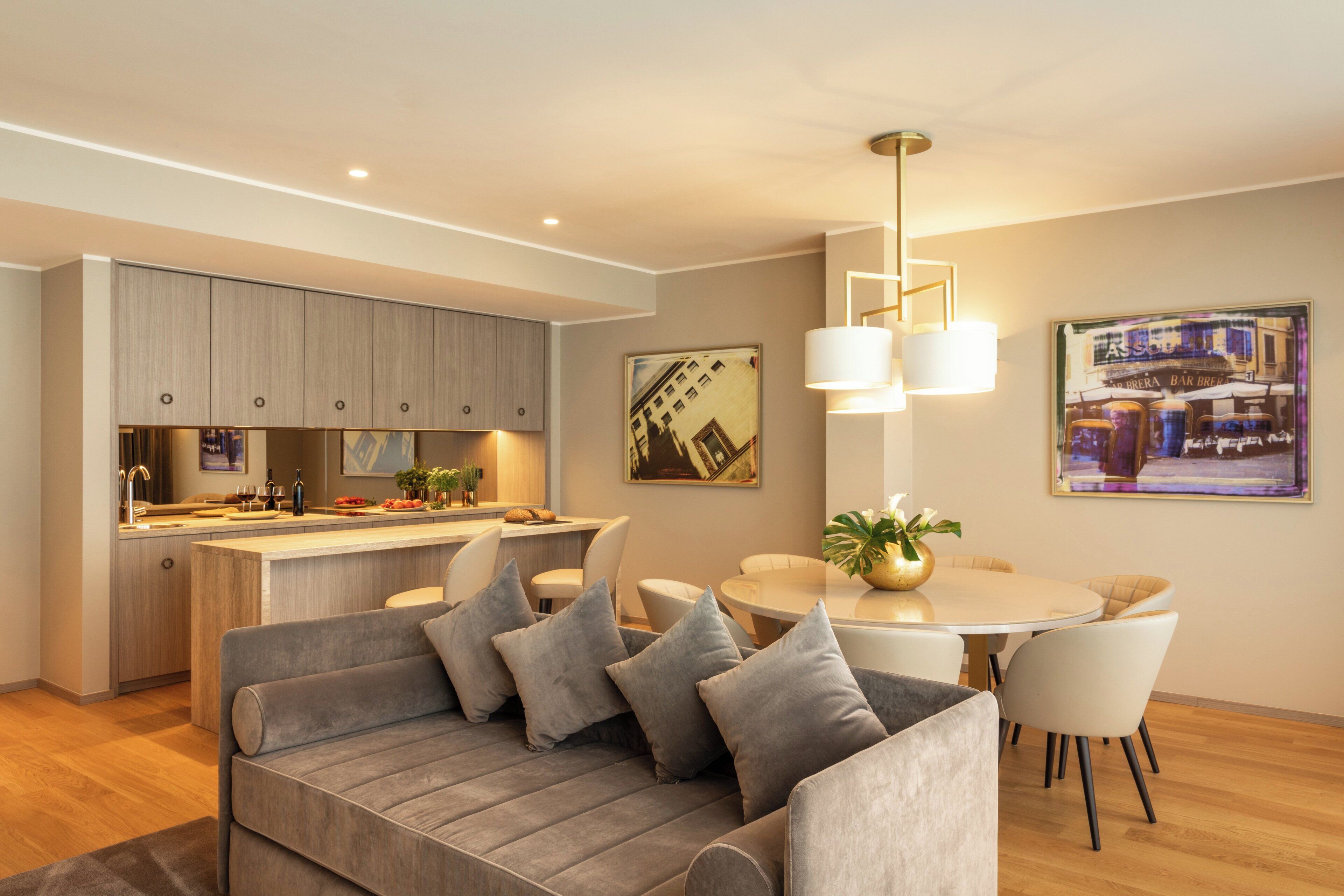 A modern kitchen with a central island, a dining area with a round table and chairs, and a sofa with cushions.