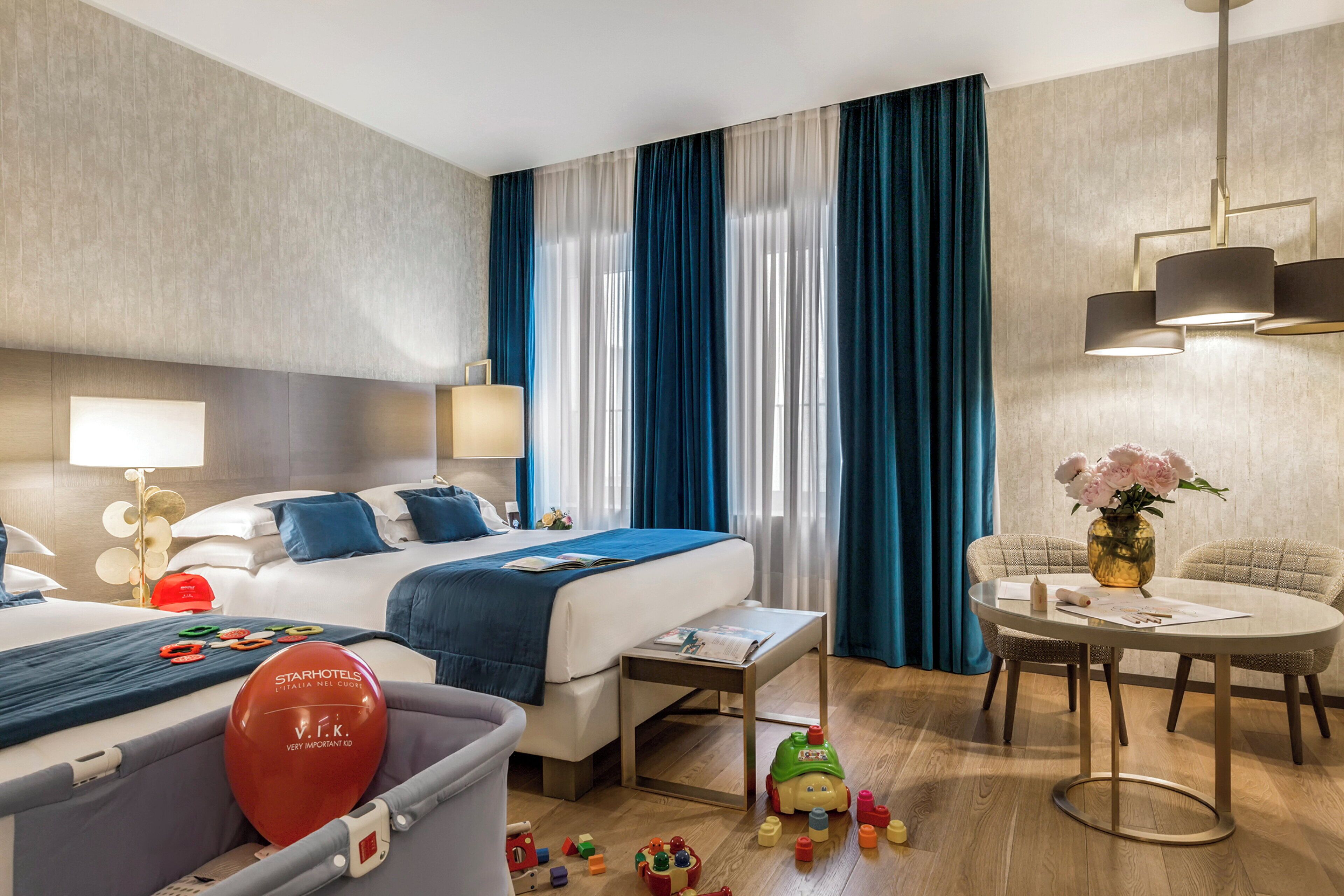 Une chambre d’hôtel comprenant un lit, des tables de chevet, une table à manger et un petit espace de jeux avec des jouets.