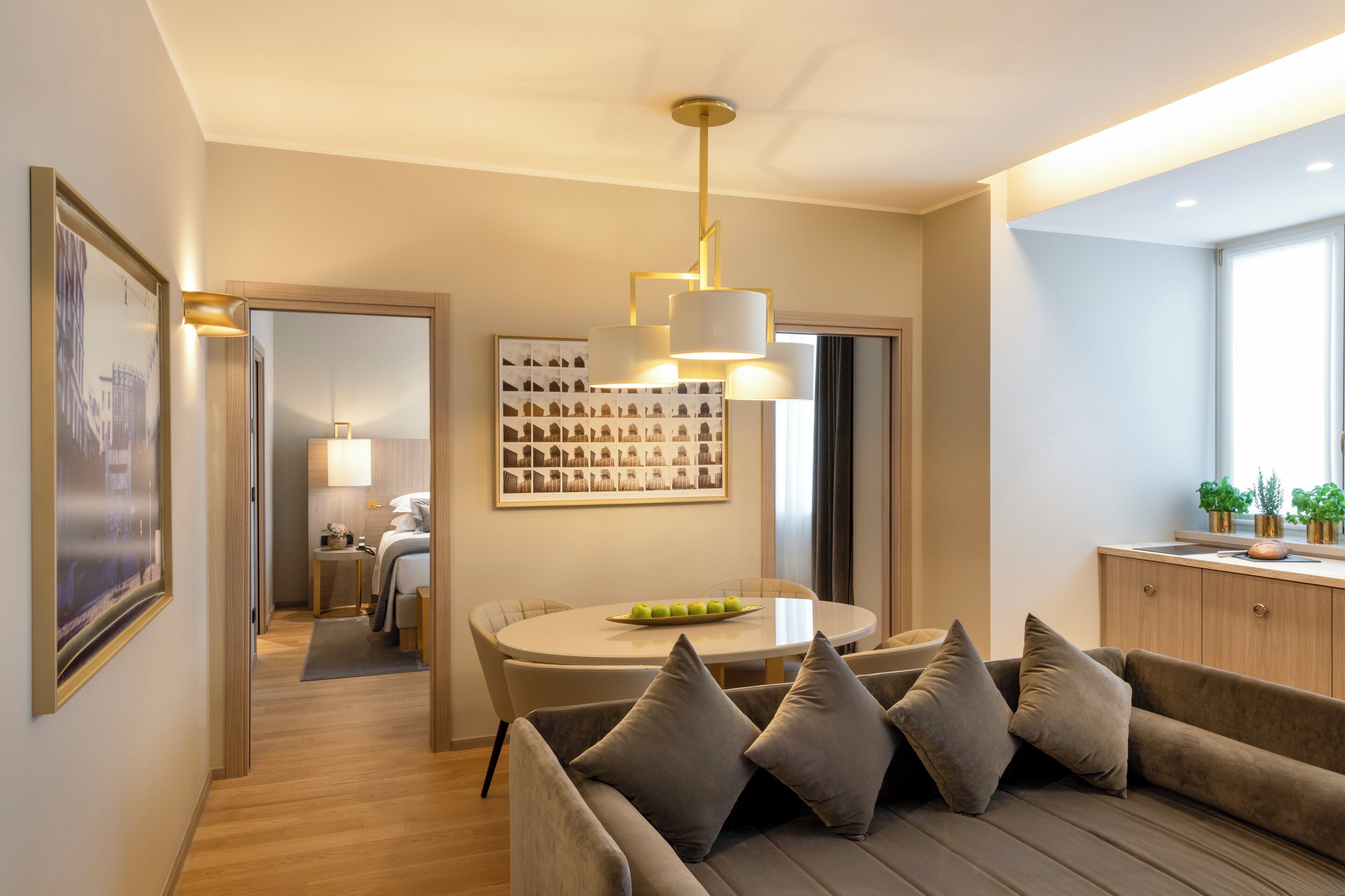 Een moderne woonkamer met een bank, een eettafel met een schaal fruit, en een wandlamp.