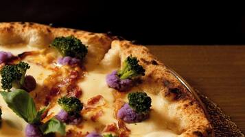 A pizza with broccoli and cheese on a wooden table.
