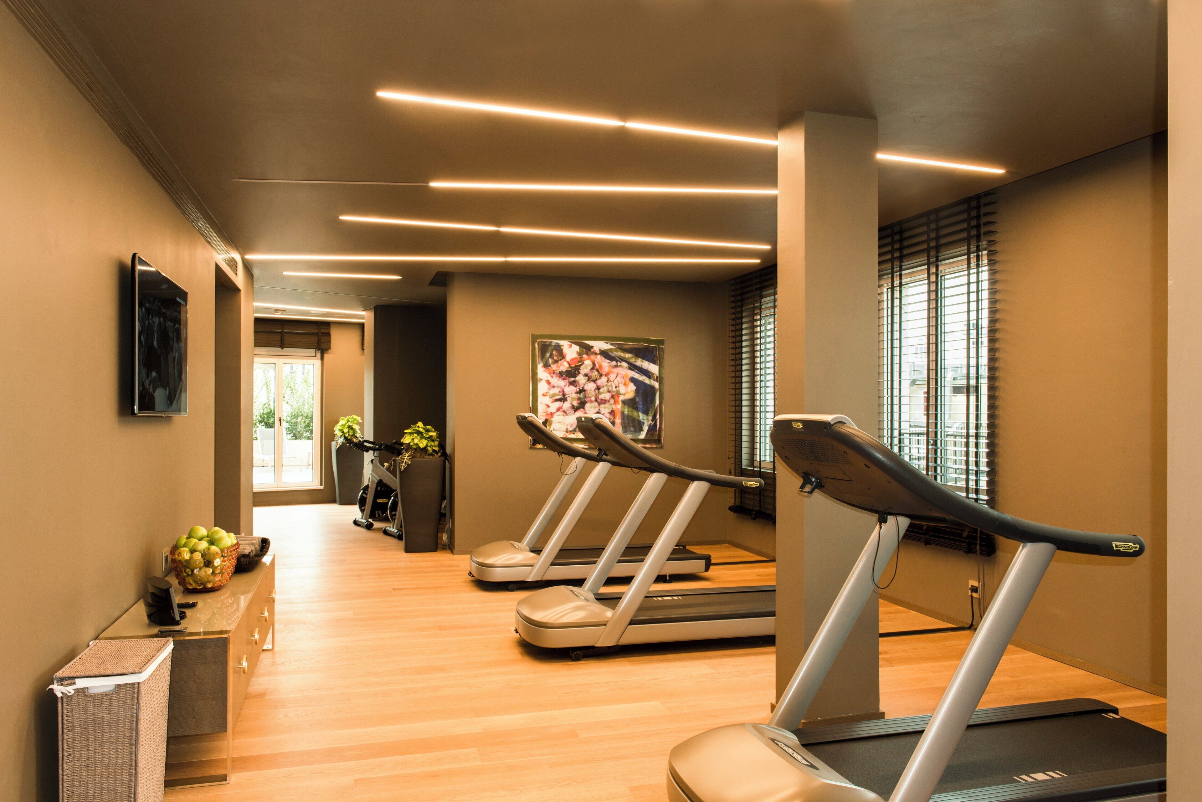 A gym with treadmills, a reception desk, and a potted plant.