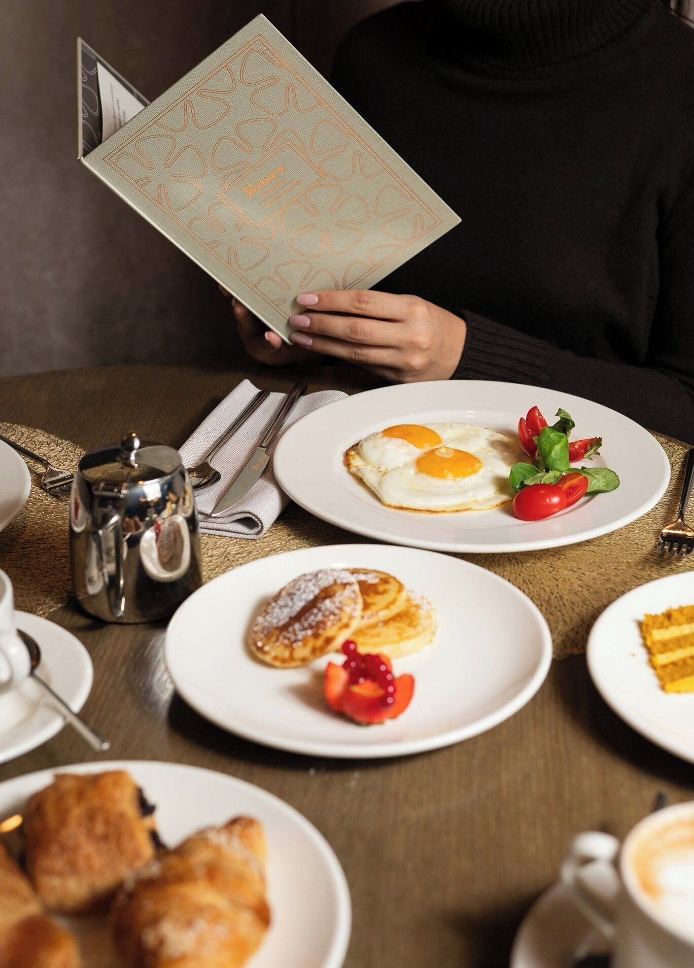 Ein Esstisch mit Tellern voller Essen, einer Kaffeekanne und einer Speisekarte.