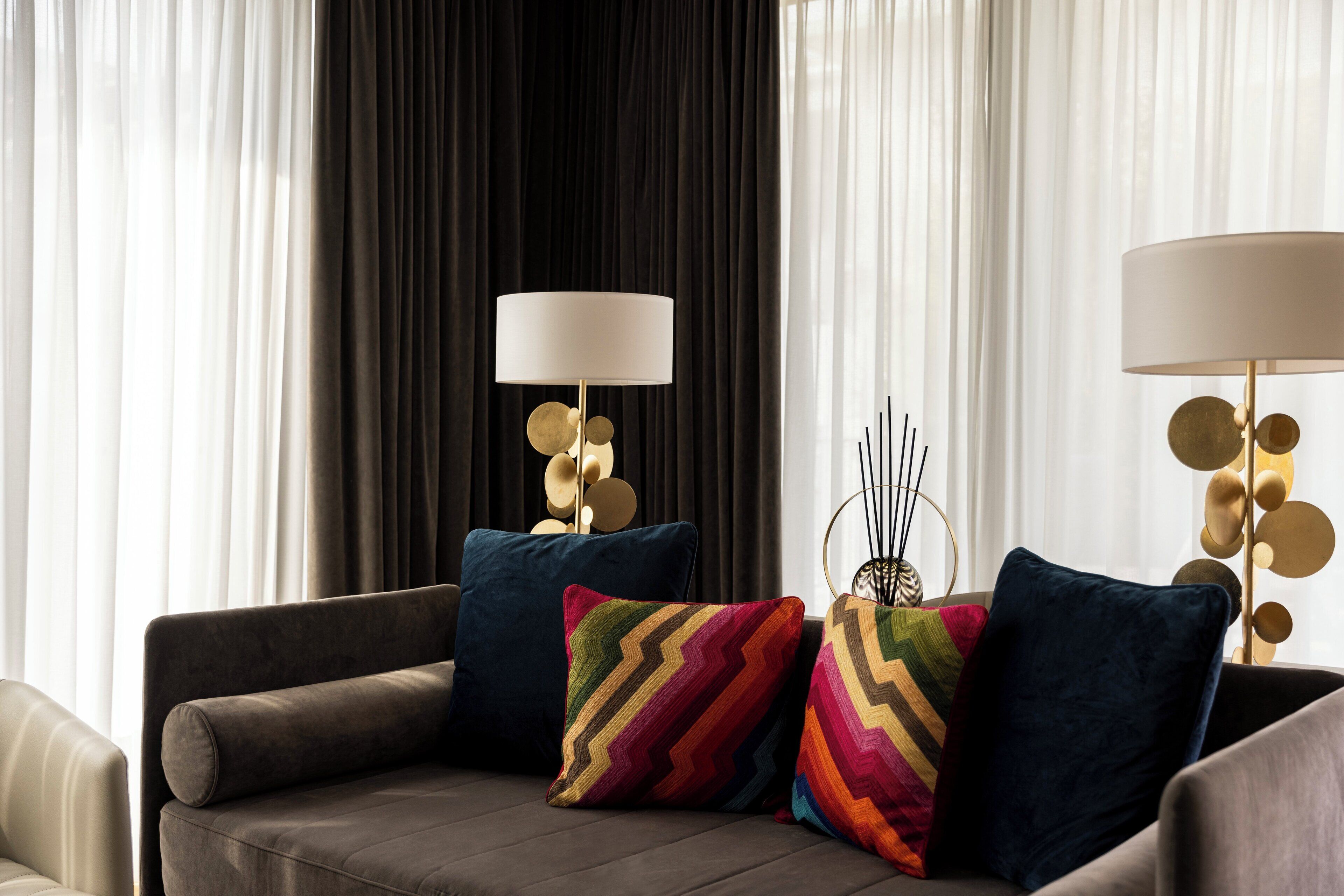 Una sala moderna con un sofá, cojines decorativos y dos lámparas.