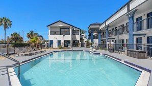 A swimming pool with a clear blue water, surrounded by a fence and lounge chairs. - Baymont by Wyndham Orlando East (Orlando)