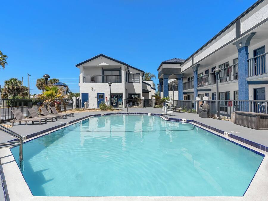Une piscine à l’eau d’un bleu cristallin, entourée d’une clôture et bordée de chaises longues.