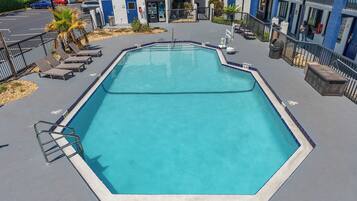 Piscina retangular com marcação de profundidade de 1,8 metros, rodeada por espreguiçadeiras e uma escada de metal.