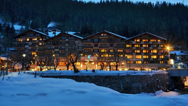 A multi-story hotel with a stone facade, multiple balconies, and a snow-covered landscape. - Silvretta Parkhotel (Klosters-Serneus)