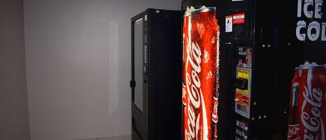 Una habitación con un refrigerador negro y una máquina expendedora de Coca-Cola.