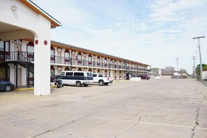 A motel with a row of rooms, a parking area, and a staircase leading to the upper level.