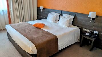 A hotel room with a large bed, two bedside lamps, a phone, and a carpeted floor.