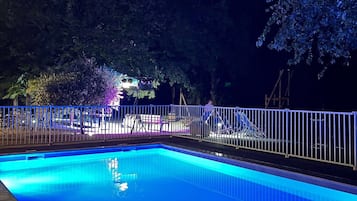 Una piscina al aire libre de temporada, sillones reclinables de piscina