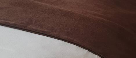 A bed with white bedding and a brown blanket.