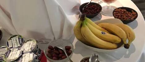 Una mesa de buffet con diversos alimentos, incluyendo plátanos, cerezas y yogur.