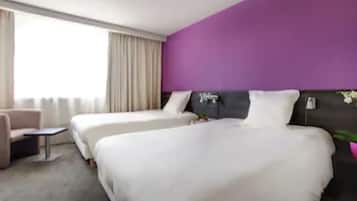 A hotel room with two beds, a sofa, a small table, and a large window with curtains.