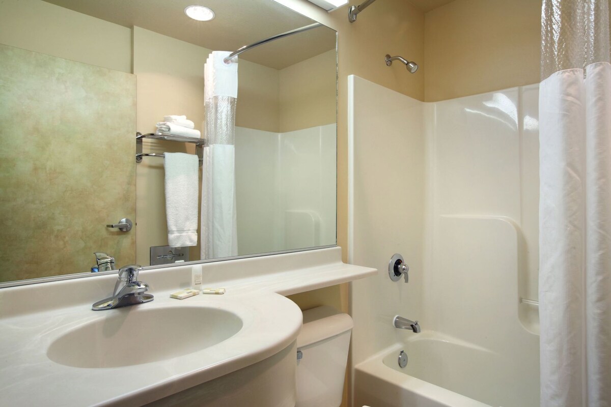 A bathroom with a sink, mirror, toilet, and bathtub.