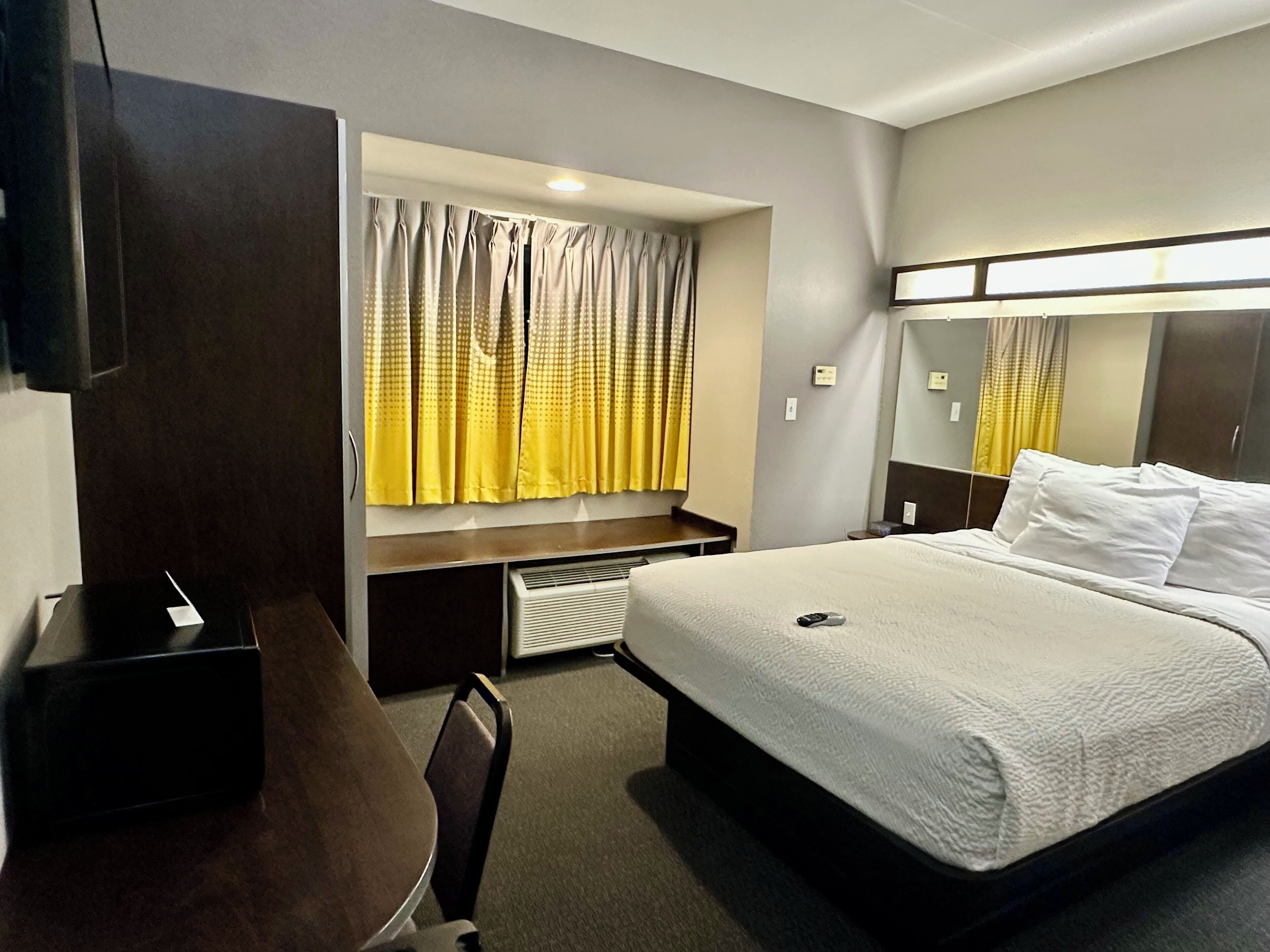 A hotel room with a bed, a desk, and a chair.