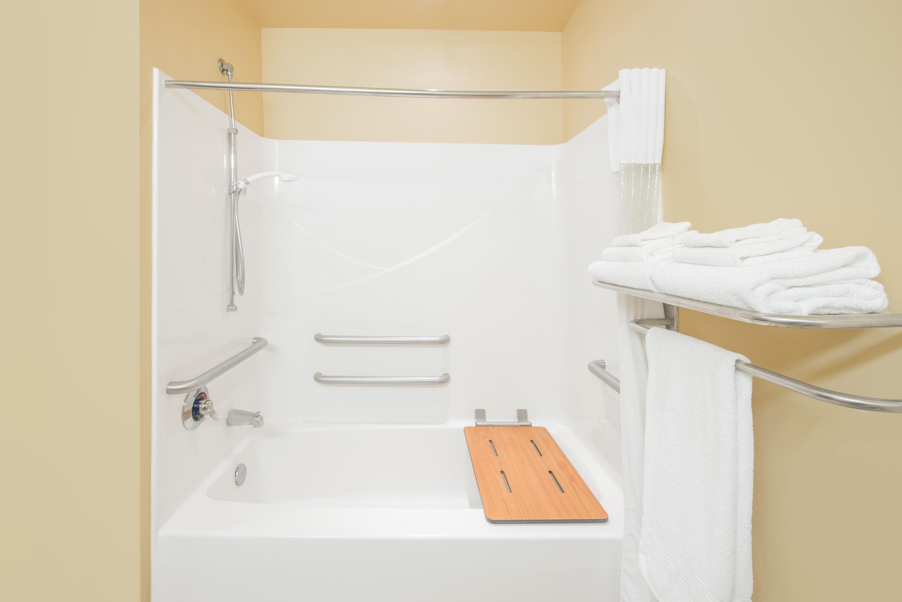 A modern bathroom with a bathtub, a shower, and a towel rack.