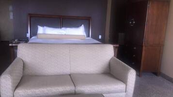 A hotel room with a bed, a sofa, a wooden cabinet, and a nightstand.