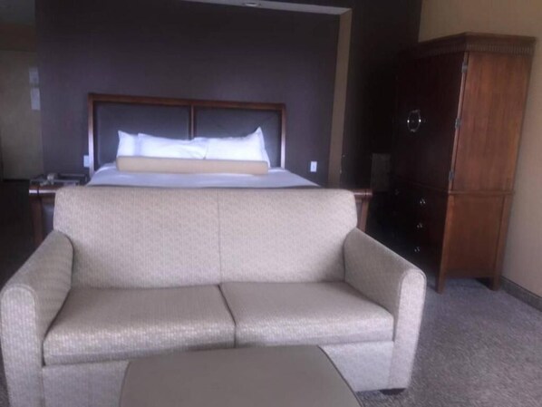 A hotel room with a bed, a sofa, a wooden cabinet, and a nightstand. - Microtel Inn & Suites by Wyndham Quincy Downtown/River Area (Quincy)