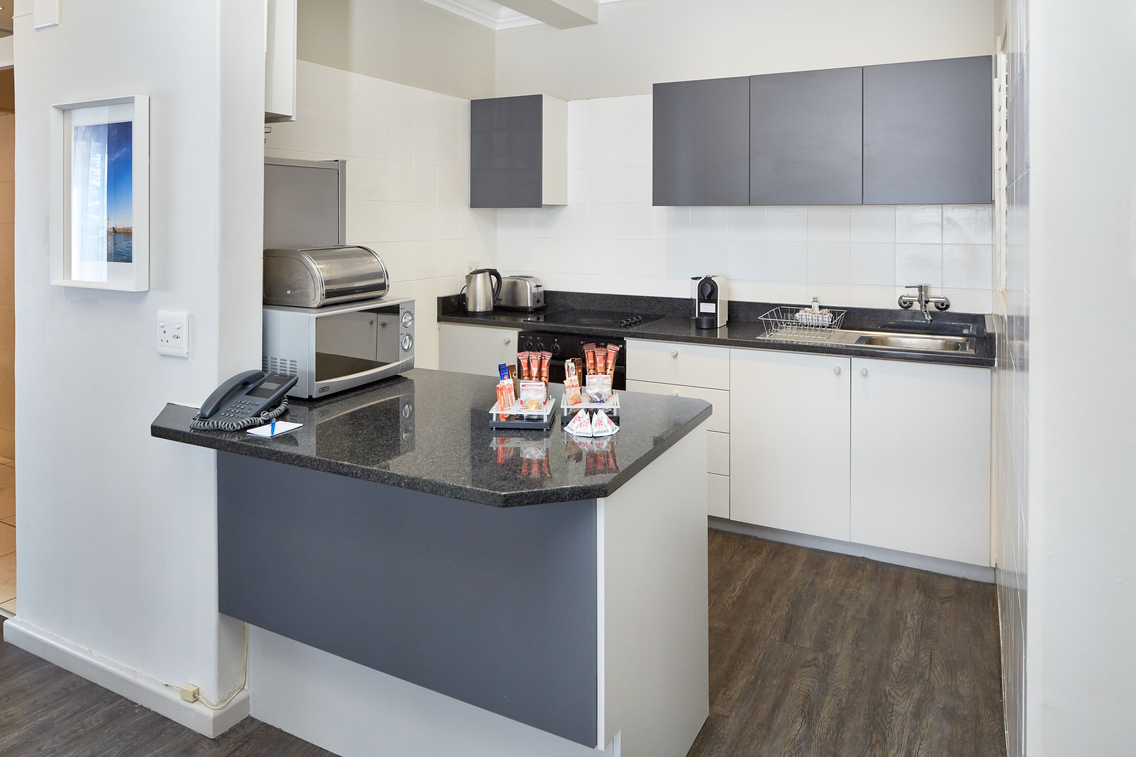 A modern kitchen with a central island, a built-in oven, a coffee maker, and a toaster.