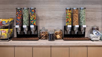 Een snackbar met verschillende bakken vol koekjes, snoep en chips.