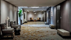 A hotel lobby with a carpeted floor, seating area with chairs, a reception desk, and a decorative wall. - New York LaGuardia Airport Marriott (East Elmhurst)