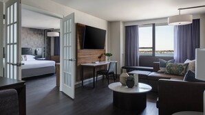 A modern hotel room with a bed, a desk, a sofa, and a TV mounted on the wall. - New York LaGuardia Airport Marriott (East Elmhurst)