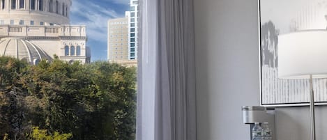 Habitación de hotel con vista a un edificio de cúpula grande, un escritorio con lámpara y un dispensador de agua.