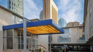 Un edificio moderno con un acceso cubierto, ventanas amplias y un área de estacionamiento.
