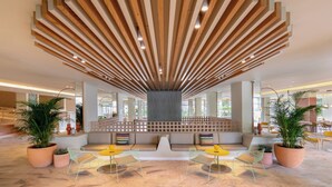 A spacious lobby with a unique wooden ceiling design, comfortable seating areas, and large potted plants. - Sol Arona Tenerife (Arona)