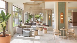 A modern lounge area with a sectional sofa, round ottomans, and a small table with chairs. - Sol Arona Tenerife (Arona)
