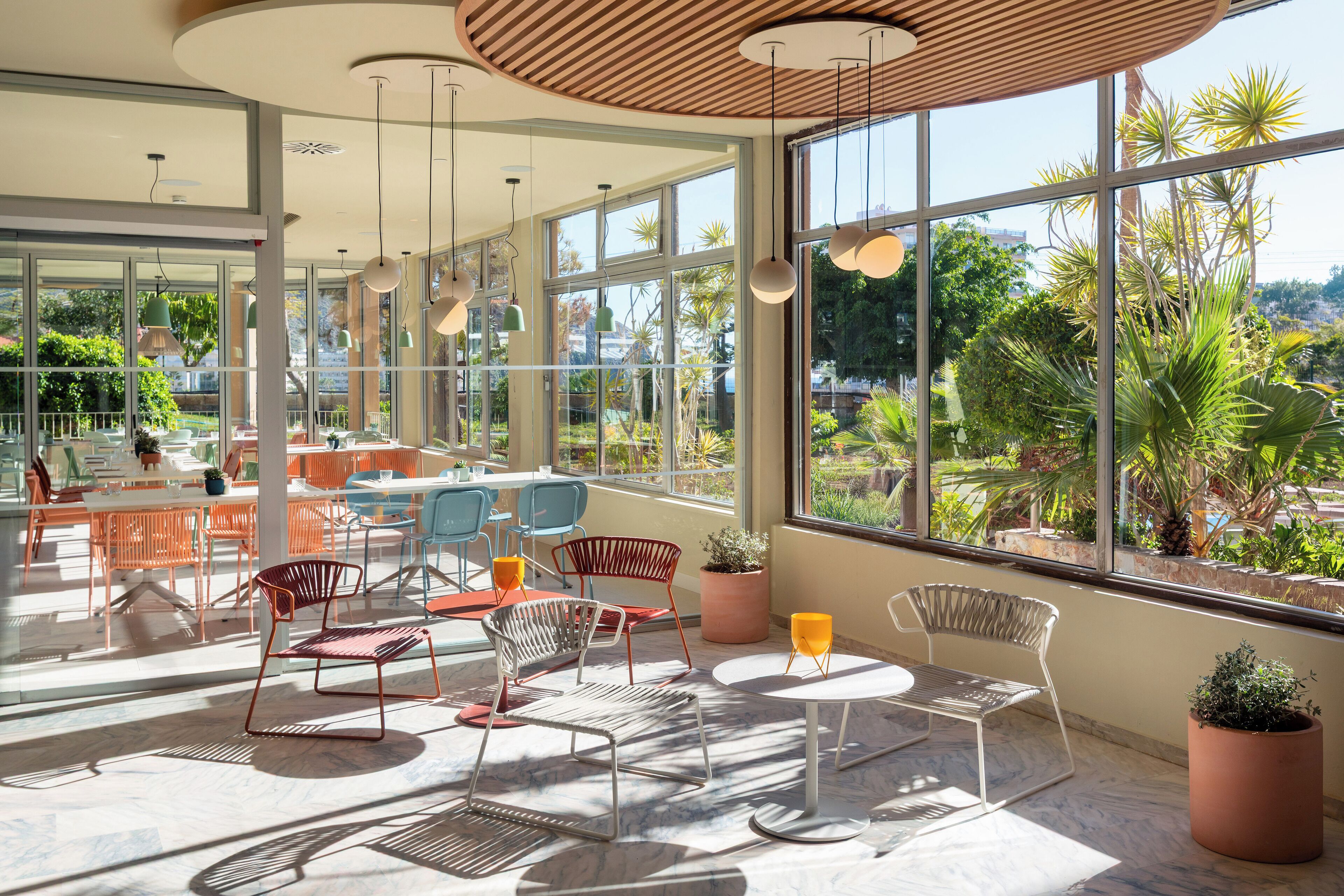 Un espacio interior amplio con ventanas grandes, muebles modernos y plantas en macetas.