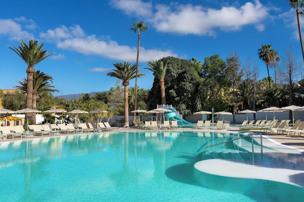 Een buitenzwembad, parasols bij het zwembad en ligstoelen