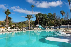 Una piscina al aire libre, sombrillas, sillones reclinables de piscina