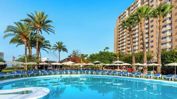 Een buitenzwembad, parasols voor strand/zwembad